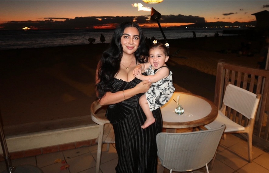 Mariah in a vertically striped dress holding her child